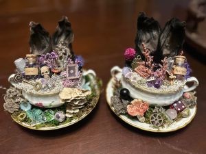 Two scenes with bunny ears in tea cups. Bottle of Garnet and Red Agate. Skull, dice, gear, key, thimble, mushrooms.